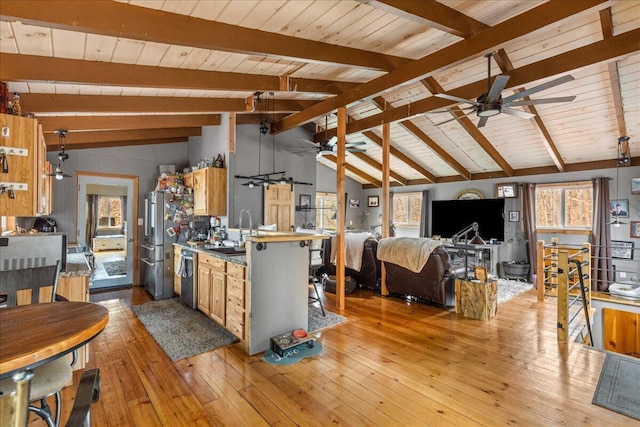 living area with vaulted ceiling with beams, a ceiling fan, plenty of natural light, and light wood-type flooring