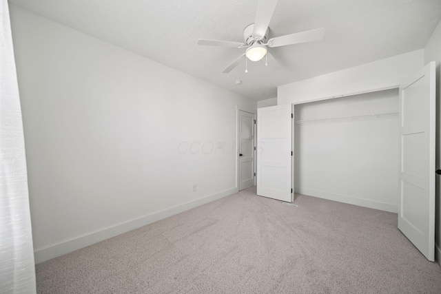 unfurnished bedroom featuring baseboards, ceiling fan, light carpet, and a closet