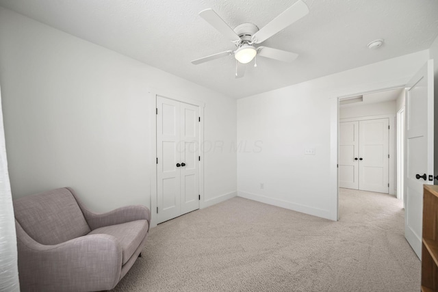 sitting room with baseboards, ceiling fan, and light carpet