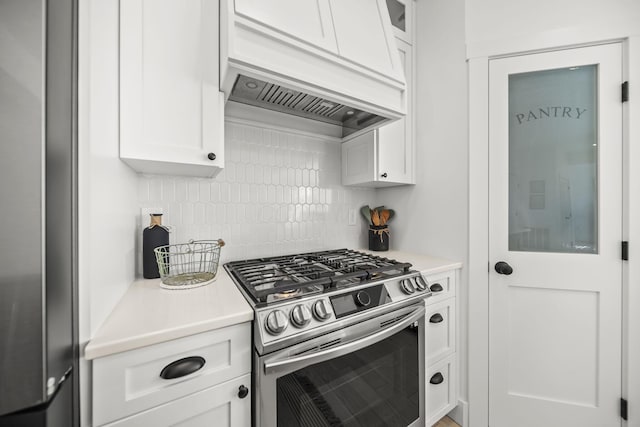 kitchen with custom exhaust hood, light countertops, white cabinetry, tasteful backsplash, and stainless steel appliances