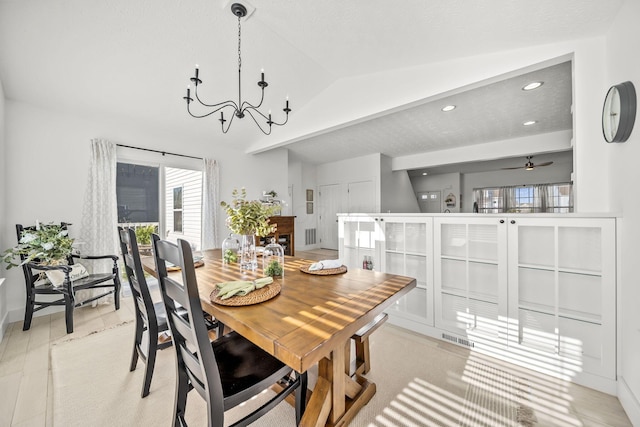 dining space featuring visible vents, ceiling fan with notable chandelier, lofted ceiling, and a wealth of natural light