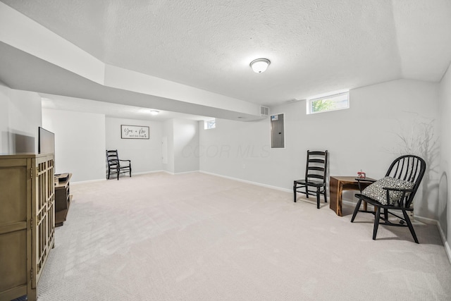 living area featuring a textured ceiling, baseboards, light carpet, and electric panel