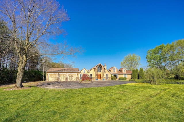 view of front of house with an attached garage, aphalt driveway, and a front yard