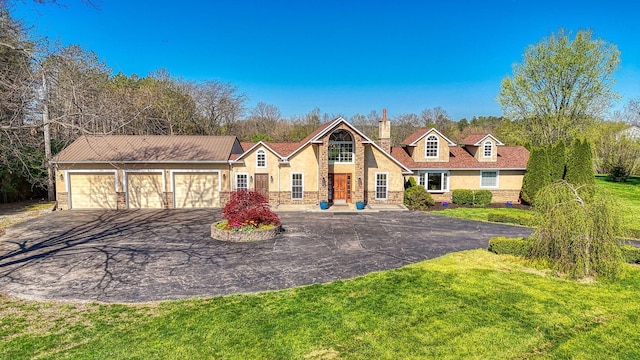 view of front of house with driveway, a chimney, a front lawn, stone siding, and stucco siding