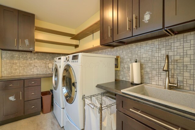 clothes washing area featuring a sink, cabinet space, and washing machine and clothes dryer