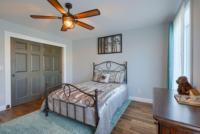 bedroom with a closet, baseboards, ceiling fan, and dark wood-type flooring