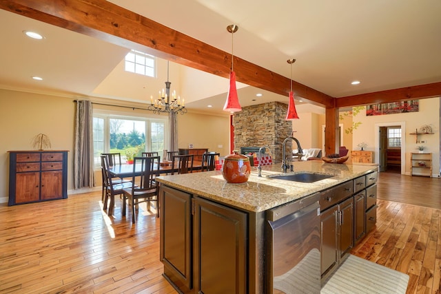 kitchen featuring beam ceiling, a sink, light wood finished floors, dishwasher, and open floor plan
