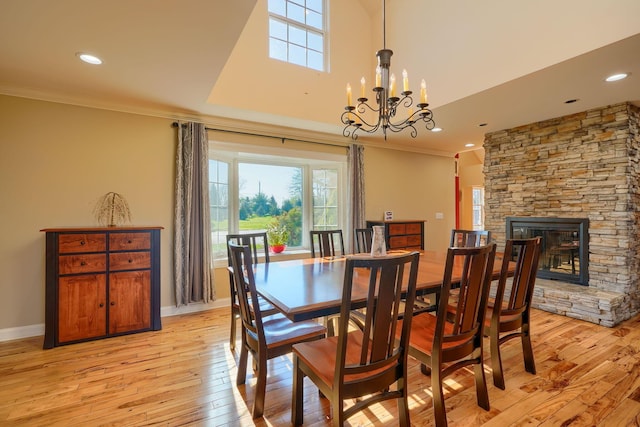 dining room with ornamental molding, a stone fireplace, recessed lighting, and light wood-style flooring