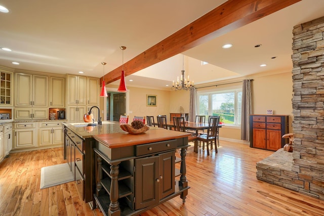 kitchen with cream cabinets, ornamental molding, a sink, and light wood-type flooring