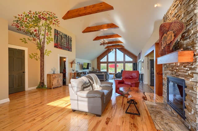 living room with beamed ceiling, a stone fireplace, light wood-style floors, baseboards, and high vaulted ceiling