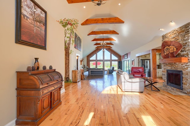 living room with high vaulted ceiling, a stone fireplace, baseboards, light wood-type flooring, and beamed ceiling