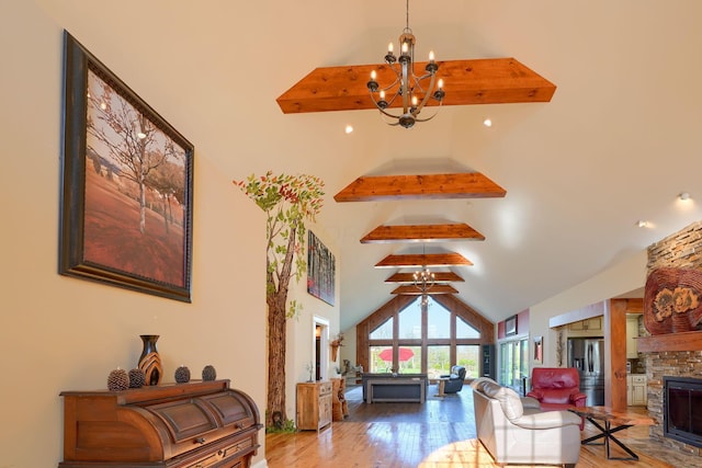 living area featuring a fireplace, wood finished floors, beam ceiling, high vaulted ceiling, and a notable chandelier