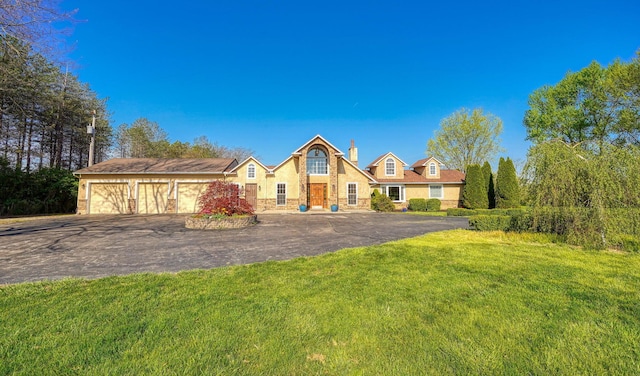 view of front of home featuring an attached garage, a front lawn, stone siding, a chimney, and driveway
