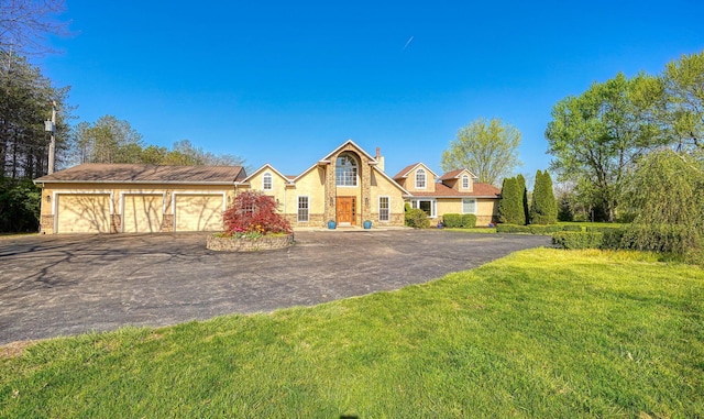 view of front facade with stucco siding, a front yard, driveway, and stone siding