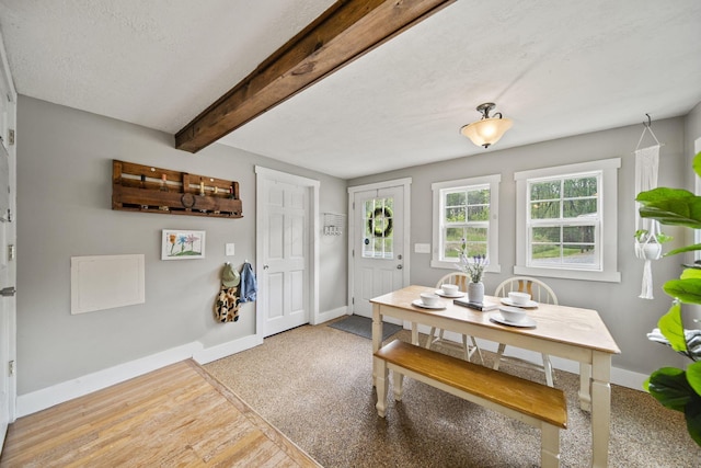 dining space featuring beamed ceiling, baseboards, and light wood finished floors