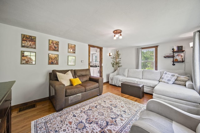 living room featuring visible vents, baseboards, and wood finished floors
