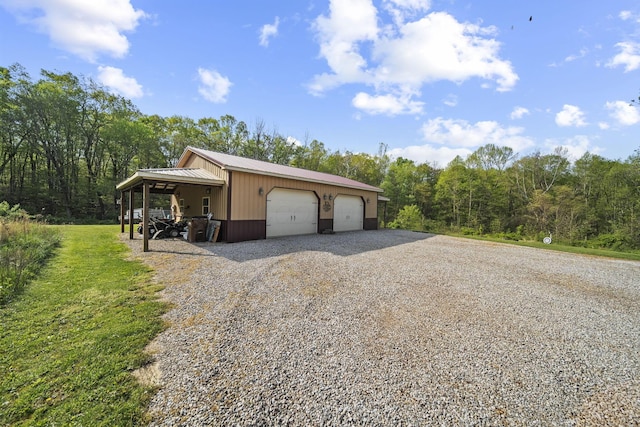 view of side of property with a detached garage, an outdoor structure, metal roof, and a forest view