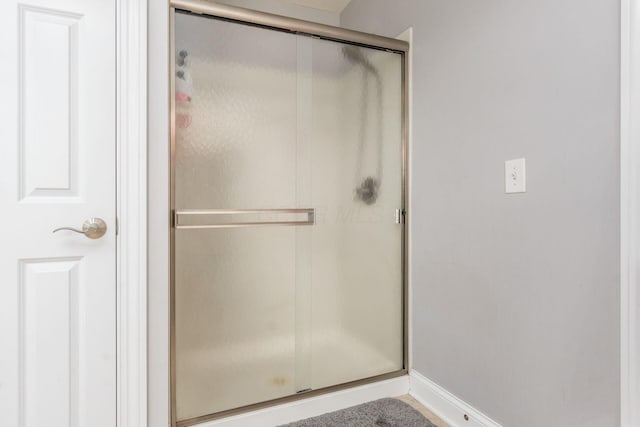 bathroom with baseboards and a stall shower