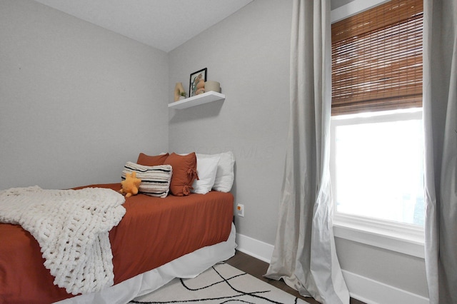 bedroom with baseboards, wood finished floors, and lofted ceiling