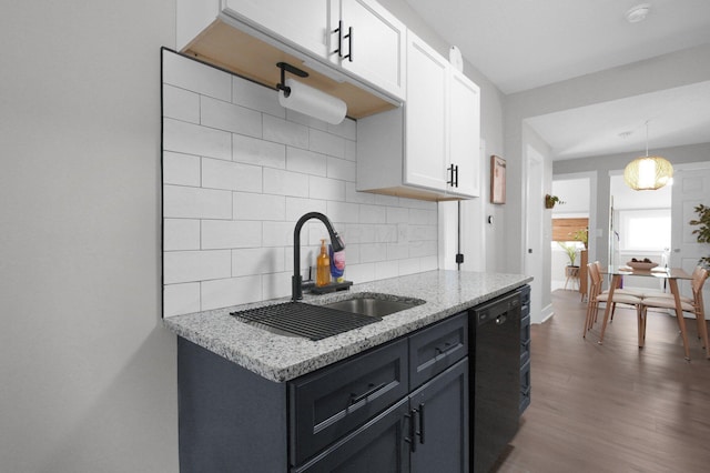 kitchen with dishwasher, white cabinets, light stone counters, a sink, and backsplash