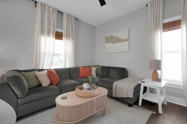 living area with baseboards, ceiling fan, and wood finished floors