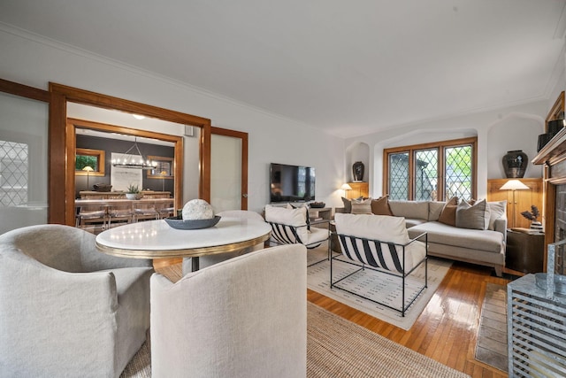 152 S Stanwood Rd, Columbus, OH 43209 - living area with crown molding, a notable chandelier, arched walkways, a fireplace with raised hearth, and hardwood / wood-style floors
