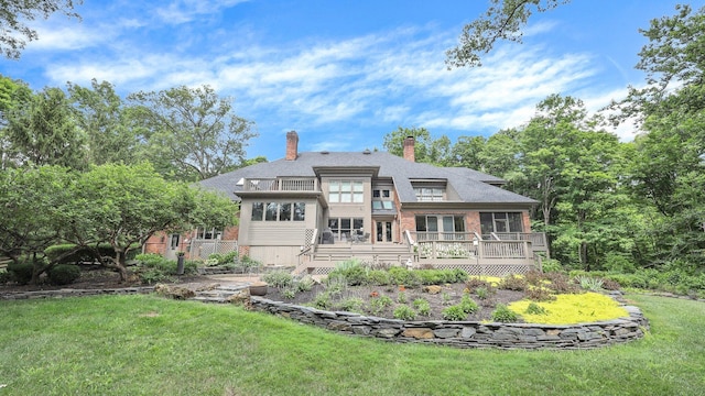 rear view of house with brick siding, a balcony, a yard, and a deck