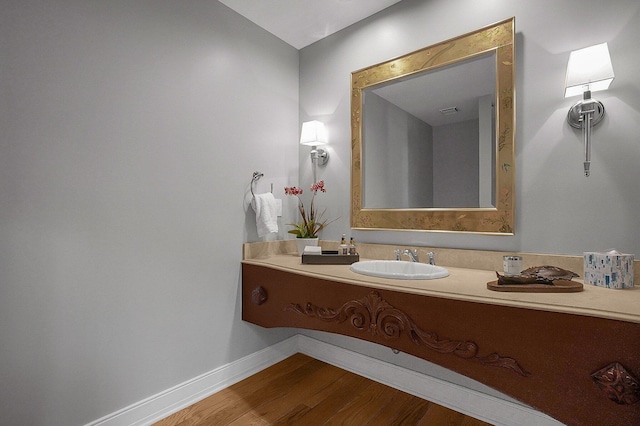 bathroom featuring baseboards, a sink, and wood finished floors