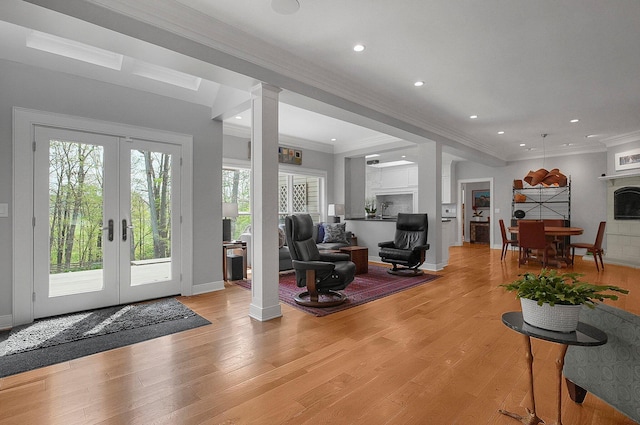 foyer featuring crown molding, baseboards, ornate columns, french doors, and light wood finished floors