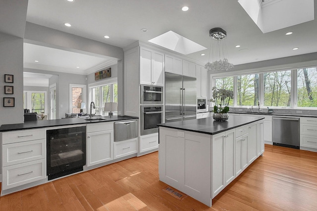 kitchen featuring beverage cooler, dark countertops, a skylight, and stainless steel appliances