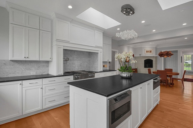 kitchen featuring a skylight, appliances with stainless steel finishes, tasteful backsplash, dark countertops, and recessed lighting