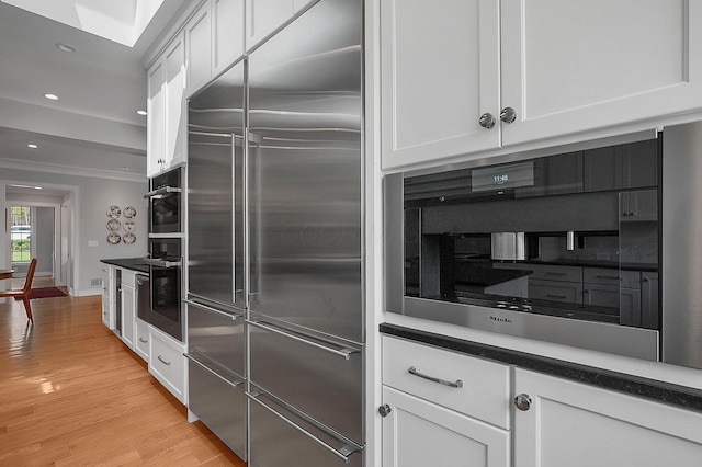 kitchen with crown molding, white cabinets, light wood-style flooring, recessed lighting, and stainless steel built in fridge