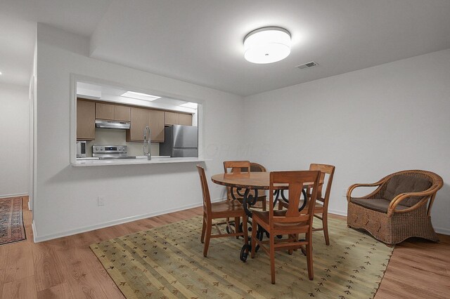 dining room with baseboards, light wood-type flooring, and visible vents
