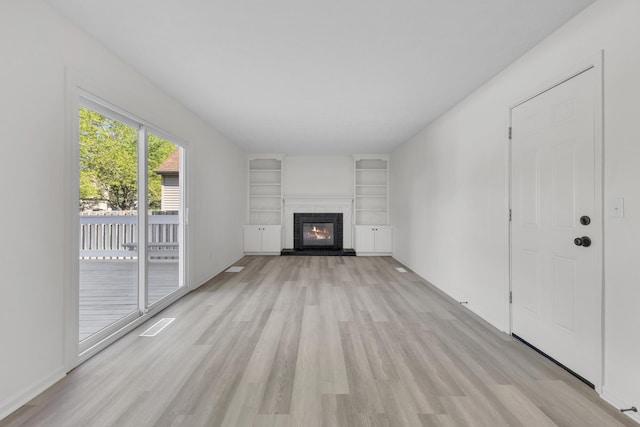7847 Maplecreek Ct, Powell, OH 43065 - unfurnished living room featuring light wood-type flooring, a brick fireplace, and built in shelves