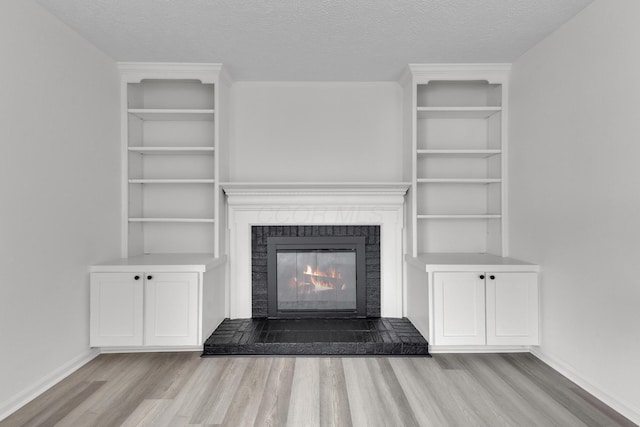 7847 Maplecreek Ct, Powell, OH 43065 - unfurnished living room featuring baseboards, a textured ceiling, a glass covered fireplace, and wood finished floors