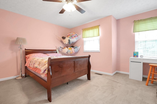 bedroom featuring a ceiling fan, baseboards, light colored carpet, and a textured ceiling