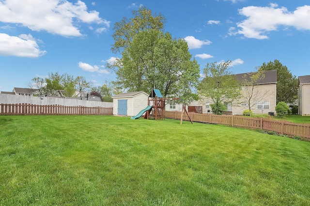 view of yard featuring a fenced backyard, a playground, a storage shed, and an outbuilding