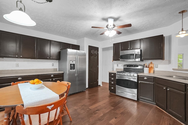 kitchen with ceiling fan, dark wood-style floors, light countertops, hanging light fixtures, and stainless steel appliances