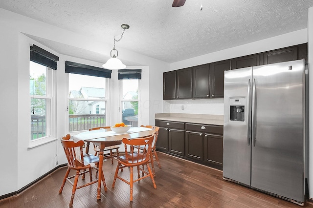 kitchen with stainless steel refrigerator with ice dispenser, a textured ceiling, dark wood finished floors, and light countertops