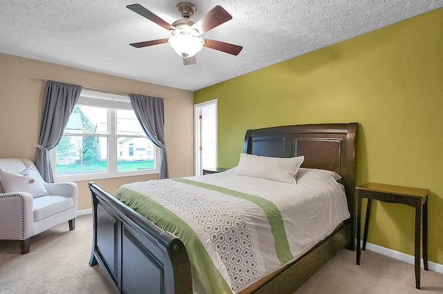 bedroom featuring baseboards, a textured ceiling, ceiling fan, and light carpet