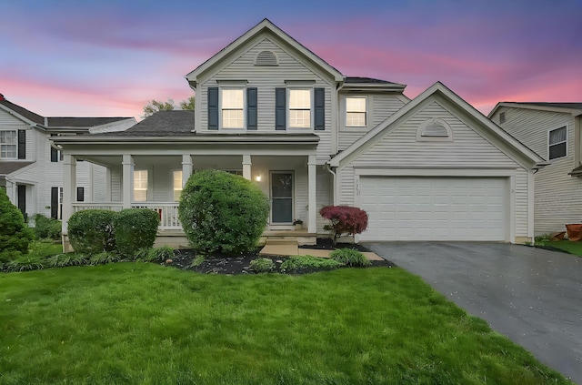 traditional-style house with a porch, aphalt driveway, and a front yard