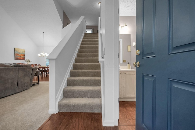 stairs with baseboards, a chandelier, and wood finished floors