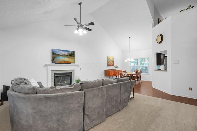 carpeted living room featuring wood finished floors, high vaulted ceiling, baseboards, ceiling fan with notable chandelier, and a glass covered fireplace