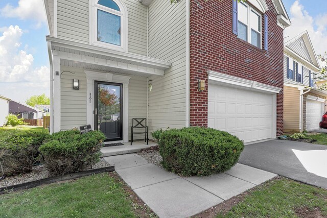 view of exterior entry featuring a porch, brick siding, an attached garage, and aphalt driveway