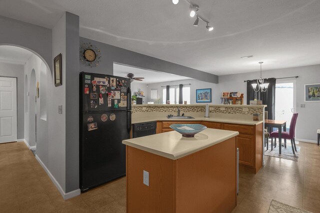 kitchen featuring light countertops, a healthy amount of sunlight, a sink, and black appliances