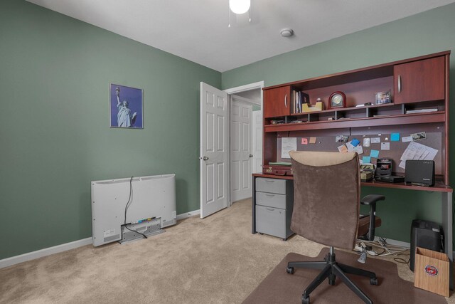 office space featuring baseboards, ceiling fan, and light carpet