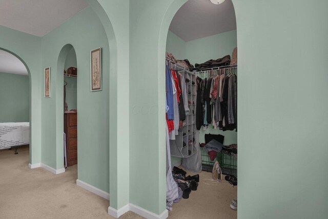spacious closet with carpet flooring and arched walkways
