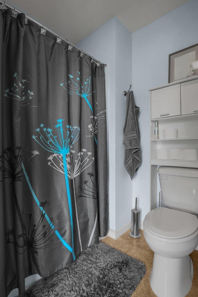 full bathroom featuring baseboards, a shower with shower curtain, tile patterned floors, and toilet