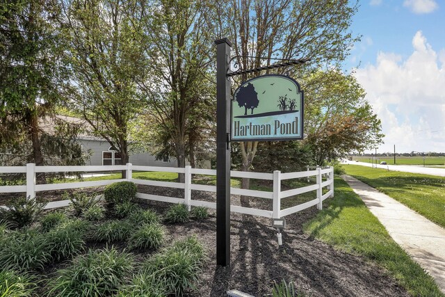 community / neighborhood sign with fence and a yard