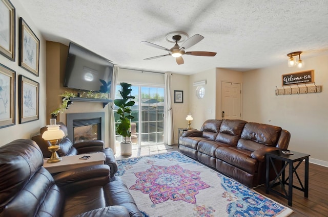 5688 Blendonridge Dr Unit 93E, Columbus, OH 43230 - living area with ceiling fan, a textured ceiling, baseboards, dark wood-style floors, and a glass covered fireplace